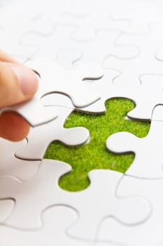 Hand embed missing puzzle piece into place, green space concept