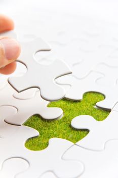 Hand embed missing puzzle piece into place, green space concept