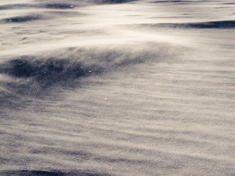 Blizzard background texture pattern: drifting snow crystals driven by strong wind creating snow surface refief