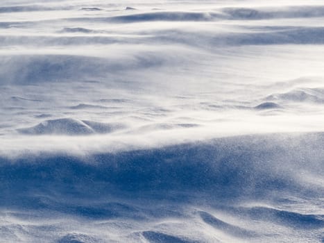 Blizzard background texture pattern: drifting snow crystals driven by strong wind creating snow surface refief