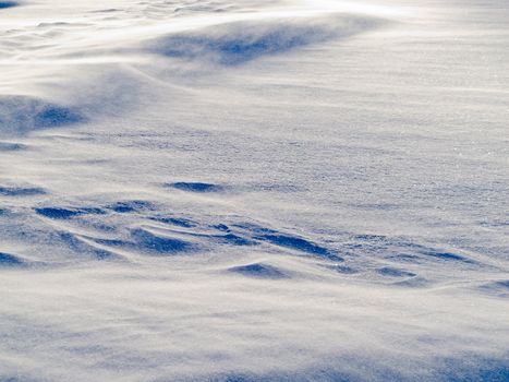 Blizzard background texture pattern: drifting snow crystals driven by strong wind creating snow surface refief