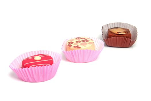 three delicious pink petit four over white background