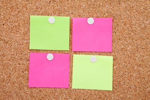 Blank sticky notes pinned on cork memo board in closeup