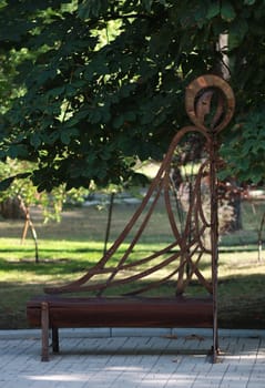 Metal forged bench in summer park with angel