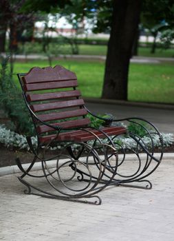 Metal form forged bench in summer park 