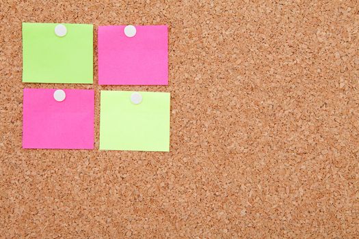 Blank sticky notes pinned on cork memo board in closeup
