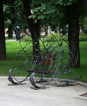 Metal form forged bench in summer park 