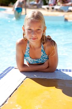 girl is posing in swim pool, looking at you