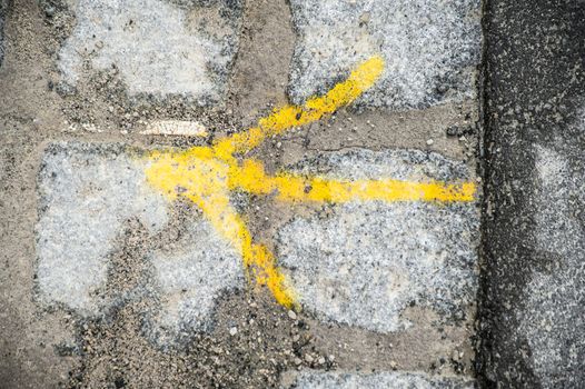 Yellow arrow on cobble stone pavement showing the right direction