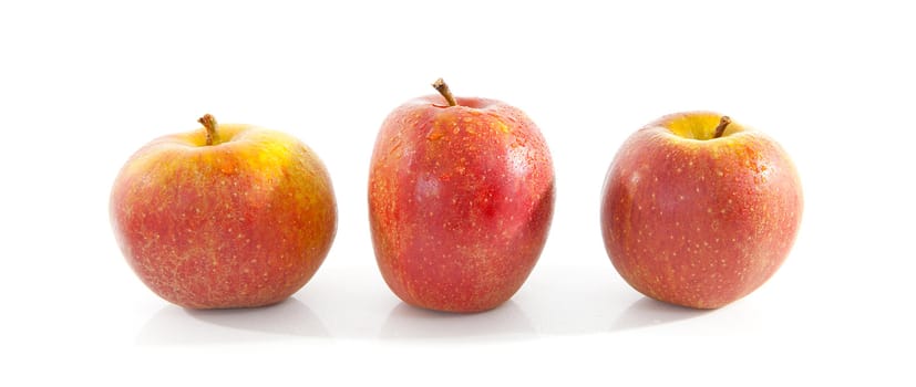 three red apples with water drops over white background