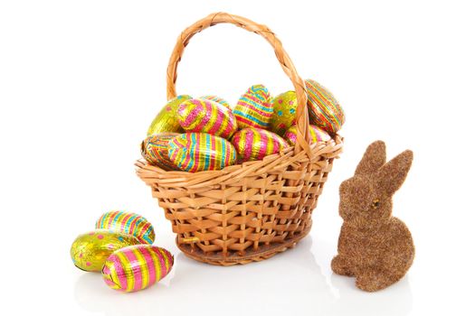 Cane basket with colorful easter eggs and bunny over white background
