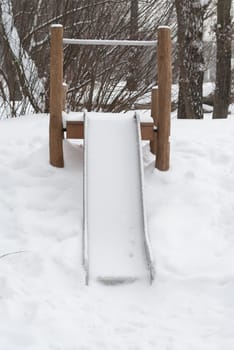 Empty childrens slide covered in snow.