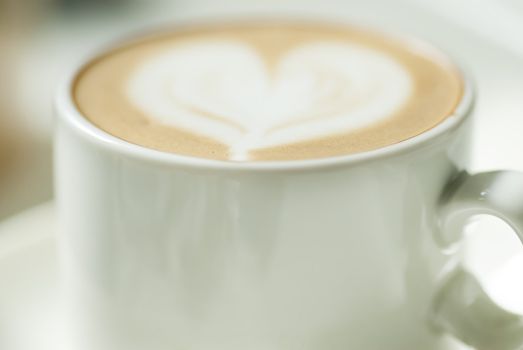 Small coffee cup with heart design in milk.