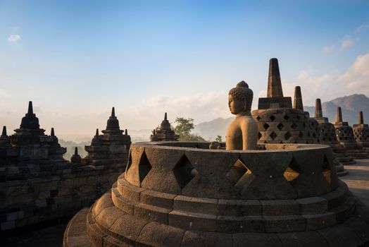 Buddha statue in open stupa in Borobudur, or Barabudur, temple Jogjakarta, Java, Indonesia at sunrise. It is a 9th-century Mahayana temple and the biggest  Buddhist Temple in Indonesia.