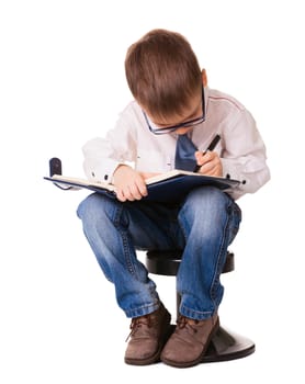 Small concentrated kid write down in organizer notebook with pen. Isolated on white background.
