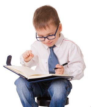 Small clever boy make notes about his plans in organizer notebook. Isolated on white background.