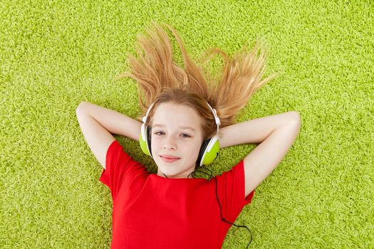 girl is listening to music with headphones on over green background