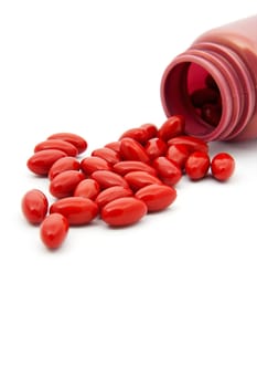 Pills laying next to bottle over white background