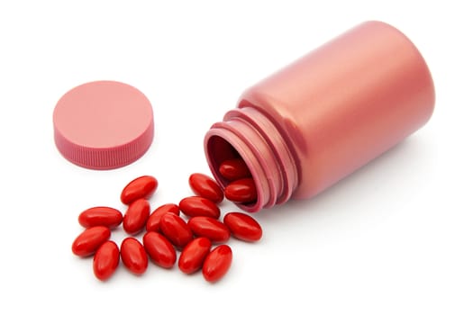 Pills laying next to bottle over white background