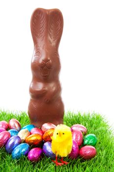 Milk chocolate easter bunny and colorful eggs on grass over white background