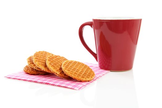 Pile of typical Dutch stroopwafels ( with syrup) on napkin near coffee cup over white background