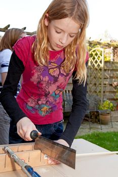Young girl is sawing a wooden stick