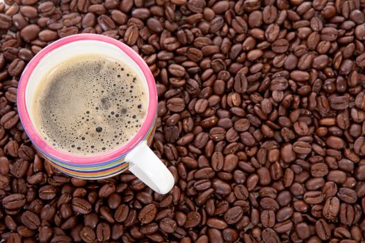 Coffee cup in background of roasted beans