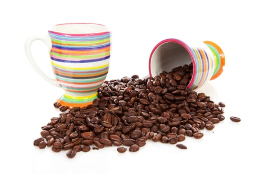 Coffee cups and pile of of roasted beans over white background