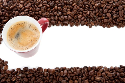 Coffee cup in background of roasted beans