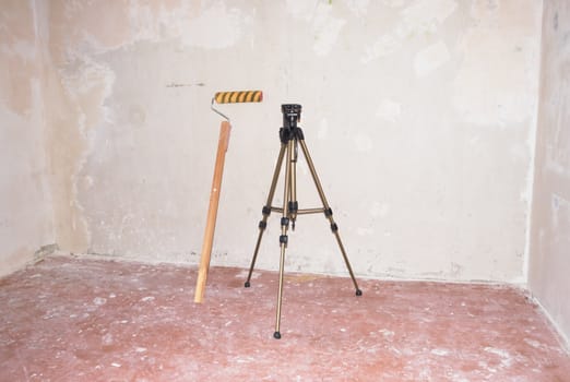 Roller for  putty and a tripod against the background of putty walls
