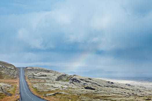 Icelandic landscape with mountains, rainbow and the road. Nature reserve on the background, Iceland