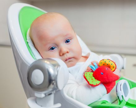 Closeup portrait of sweetest baby girl playing with a colorful mobile toy