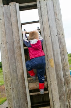 little boy climbing a ladder at the park