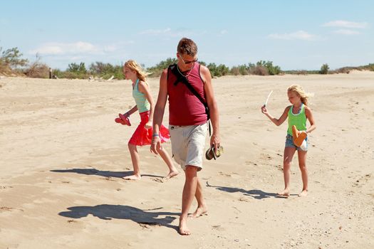 Family ( father and two daughters) walking on the beach