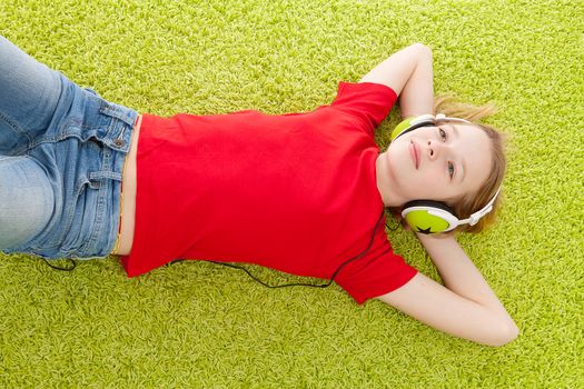 girl is listening to music with headphones on green matt
