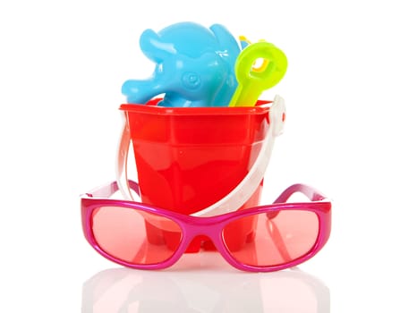 Colorful beach accessories; plastic toys and sunglasses over white background