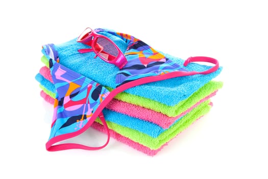 Pile of towels with bikini and pink sunglasses ovwe white background