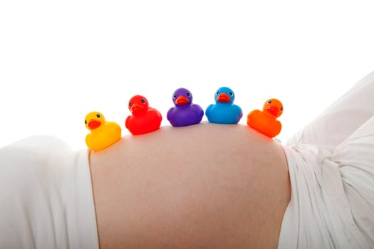 Pregnant belly with colorful rubber ducks over white background