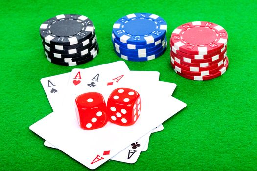 winning poker hand of four aces playing cards and red dice on green background