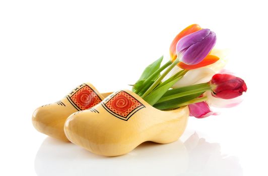 Pair of traditional yellow wooden shoes with colorful tulips isolated on white background