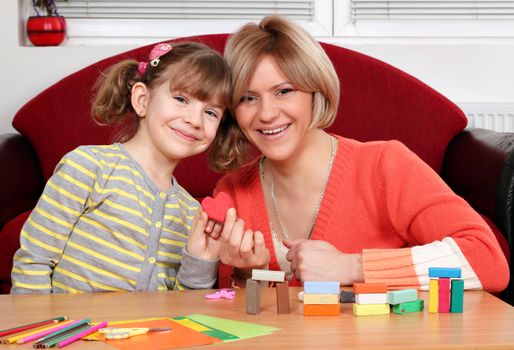 happy mother and daughter play with plasticine and make heart