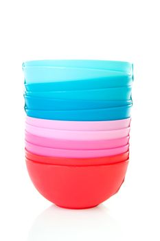 Pile of colorful plastic bowls over white background