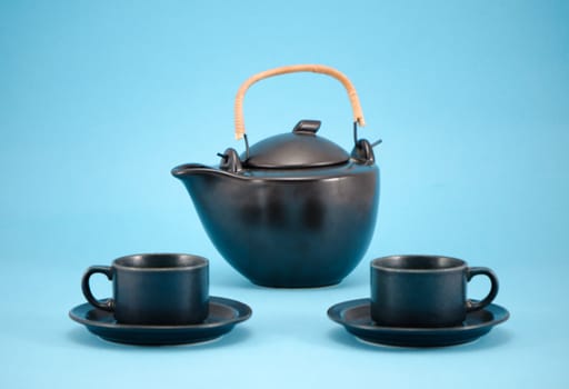 beautiful morning drink dish composition retro black teapot and small cups in saucers on blue background.