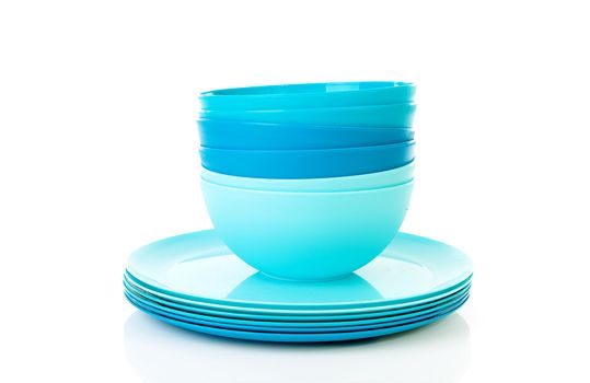 Pile of blue plastic plates and bowls over white background