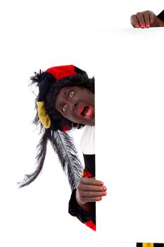 Zwarte piet ( black pete) typical Dutch character part of a traditional event celebrating the birthday of Sinterklaas in december over white background is holding empty text board 
