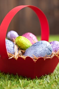 Red basket with Chocolate Easter eggs in an outdoor setting