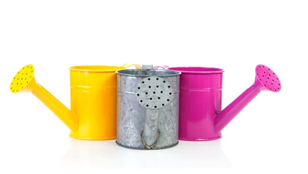 Three colorful watering cans over white background