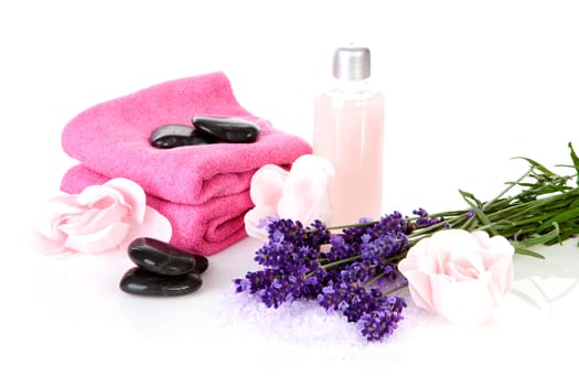 Spa accessories: stacked black pebbles stones, pink towels and lavender flowers over white background