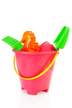 Plastic beach toys in bucket over white background