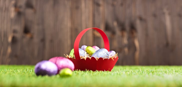 Red basket with Chocolate Easter eggs in an outdoor setting